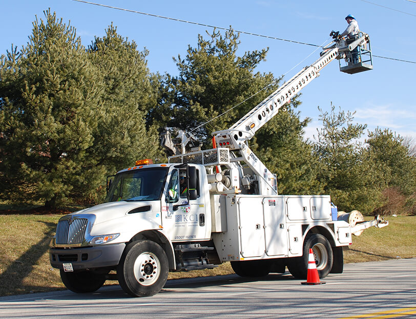 A worker in a bucket truck inspects a power line