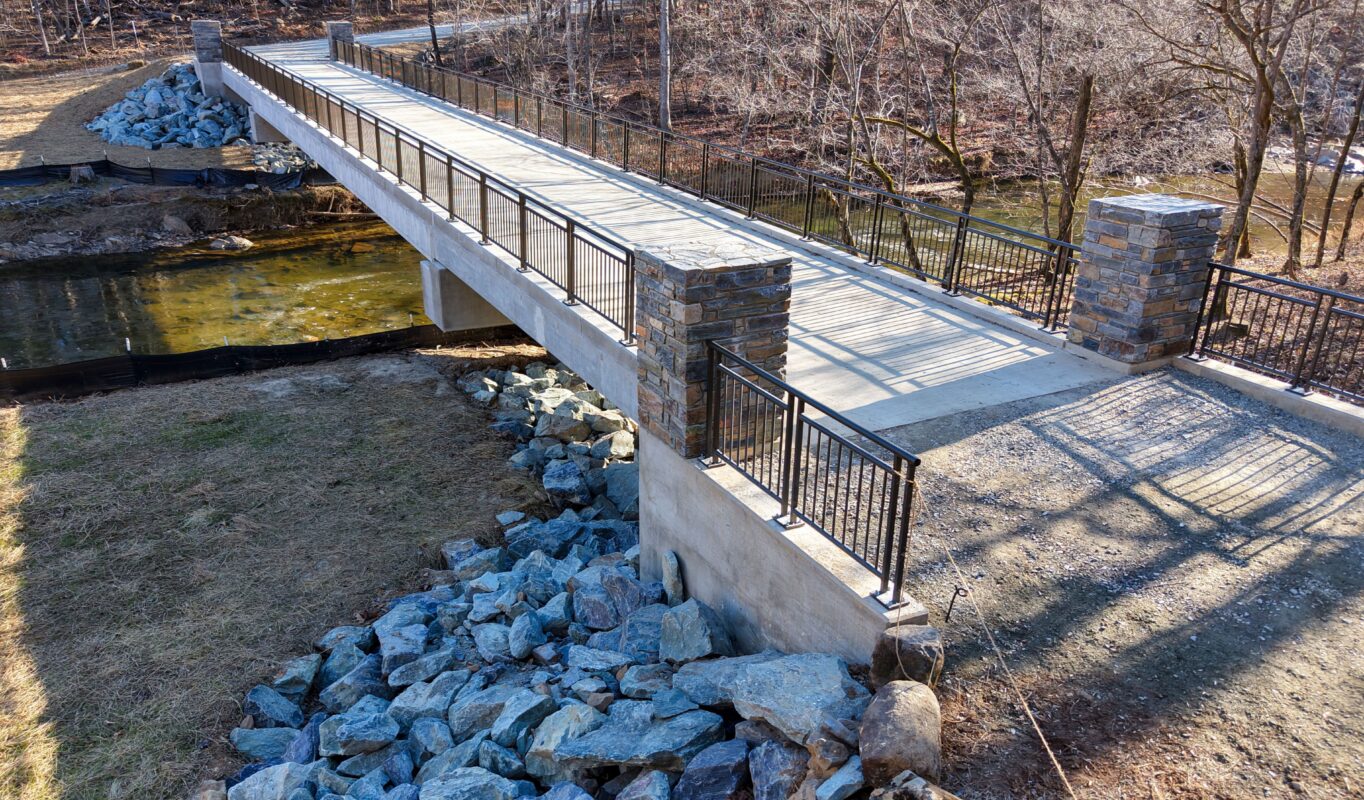 Finished bridge over New Hope Creek with stone-accented abutments and stabilized riprap banks